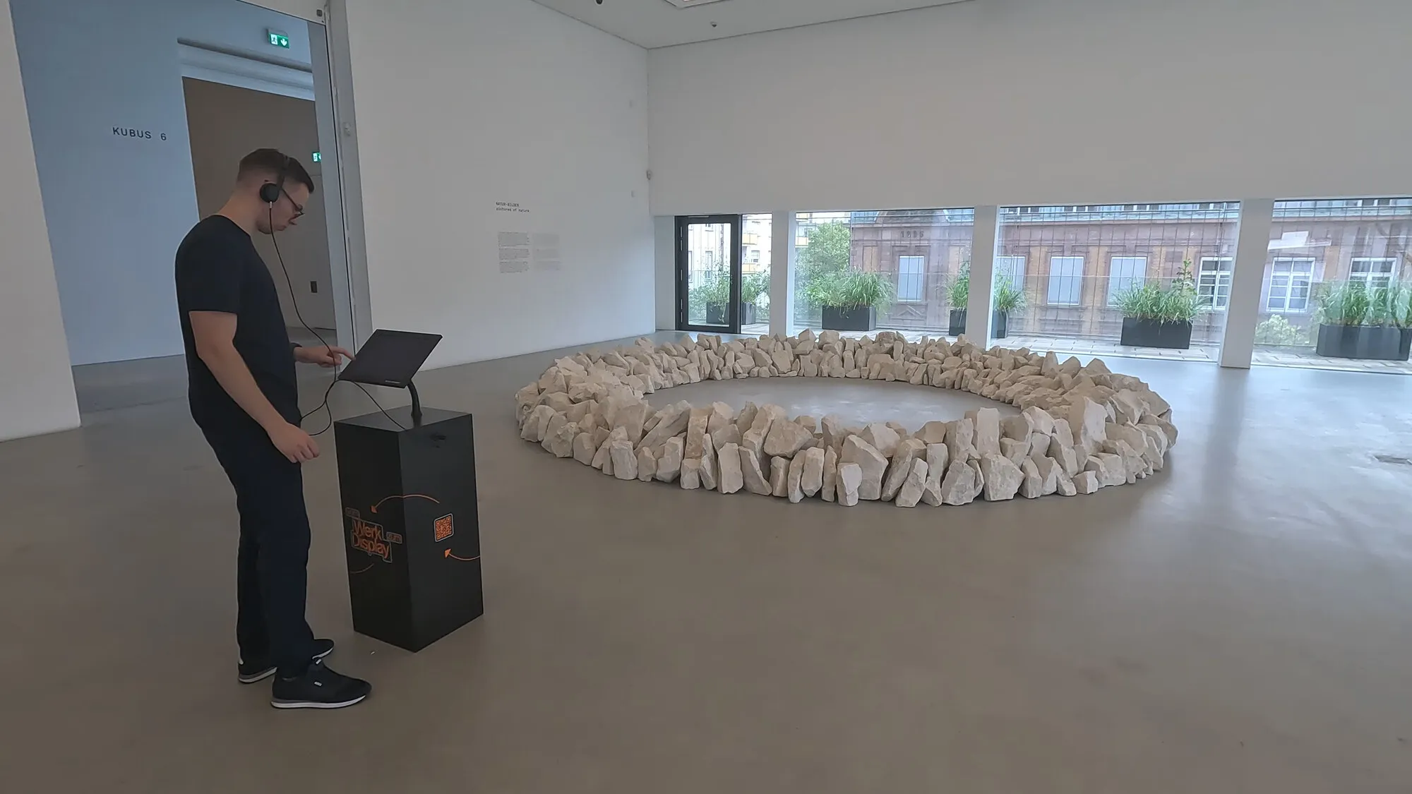 Kiosk izložbe sa slušalicama u sali Kunsthalle Mannheim, uz kameni krug Richarda Longa.