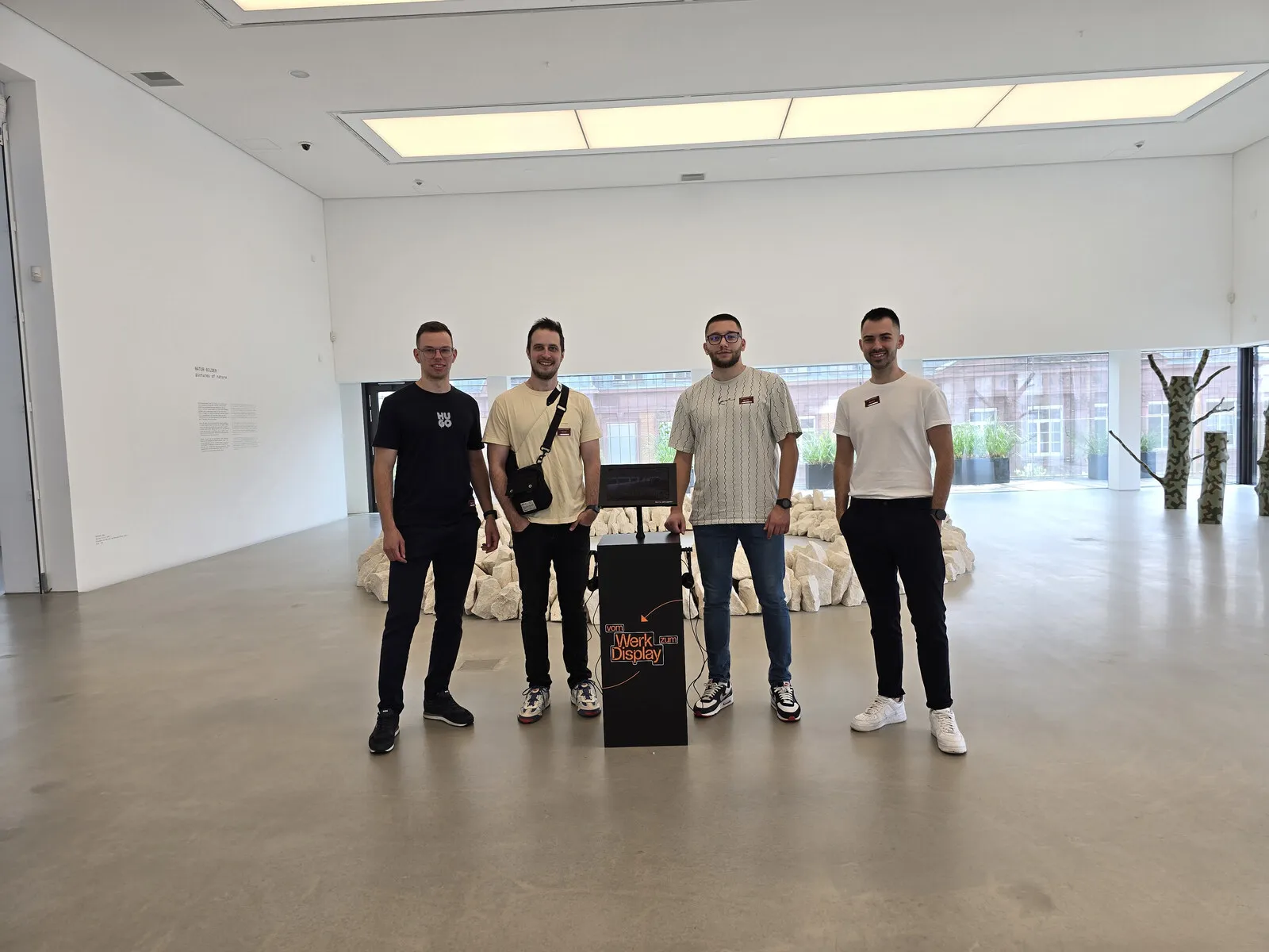 Četiri člana tima stoje oko crnog Werk zum Display kioska u galeriji.